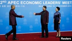 U.S. President Barack Obama (L) shakes hands with China's President Xi Jinping as Xi's wife, Peng Liyuan, looks on, during the APEC Welcome Banquet in Beijing, Nov. 10, 2014.