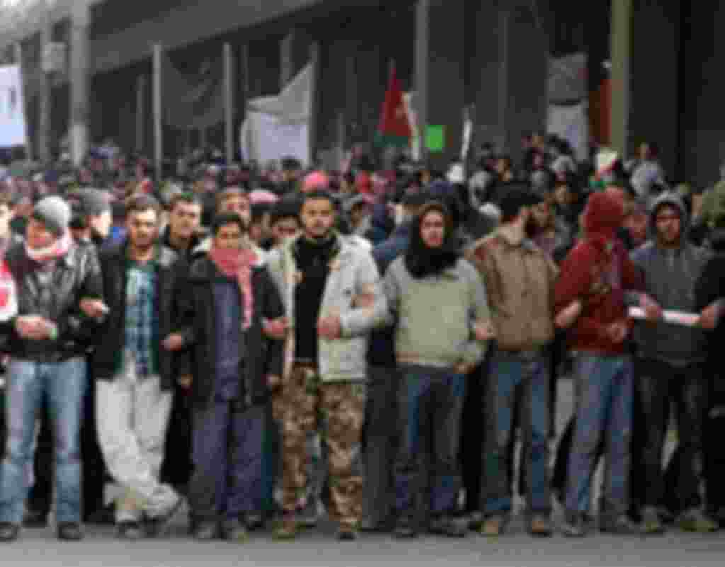 Jordanian protesters line up after pro-government supporters pelted them with stones, injuring six people during a protest at the camp in central Amman, March, 25, 2011