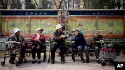 FILE - A group of elderly women rest in their wheelchairs at a residential compound in Beijing, China.