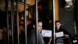 Customer Amr El Gohary, right, and his friend pose for a photograph with plastic plaques that translate to inmates with numbers, as they wait for their food, at prison-themed restaurant 'Food Crime' in the Nile Delta city of Mansoura, 110 kilometers (70 miles) north of Cairo, Egypt. The motif has even drawn policemen like Gohary, impressed by "amazing decor" and amenities like handcuffs and a metal cage that allow him a role reversal. 