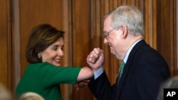 House Speaker Nancy Pelosi of Calif., left, and Senate Majority Leader Mitch McConnell of Ky., right, bump elbows as they attend a lunch on Capitol Hill in Washington, March 12, 2020. 