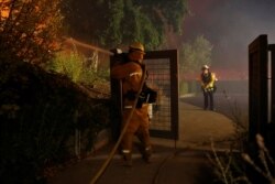 A firefighter hoses a hot spot while battling the Kincade Fire in Geyserville, Calif., Oct. 24, 2019.