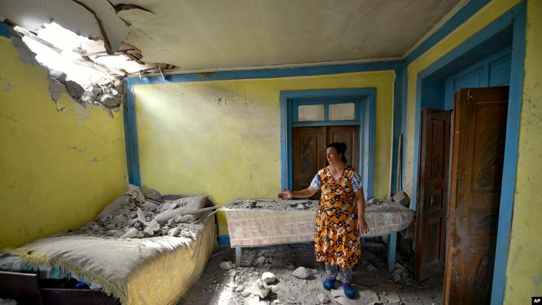 Seorang perempuan menunjukkan rumahnya yang rusak terkena tembakan dari pasukan Armenia di wilayah Tovuz, Azerbaijan, 14 Juli 2020.