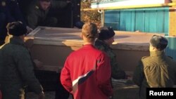 FILE - Russian servicemen unload a coffin containing the body of Vadim Kostenko, a member of the Russian air force's support staff in Syria, from a truck near his family's house in Grechanaya Balka, Russia, Oct. 27, 2015.