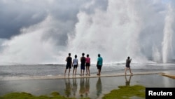 ARCHIVO - Un grupo de cubanos observa las olas que se estrellan contra el Malecón de La Habana mientras el huracán Milton pasa cerca de la costa cubana, el 9 de octubre de 2024. Muchos cubanos se lanzan al mar para intentar llegar a EEUU en peligrosos viajes.