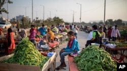 A young boy selling vegetables sits on a hand cart without wearing a mask on the outskirts of New Delhi, India, Nov. 20, 2020. 