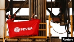 Trabajadores petroleros de Venezuela sostienen una bandera con el logo de PDVSA en una instalación de la Faja del Orinoco, en Anzoátegui, el 16 de abril de 2025. (ARCHIVO: REUTERS)