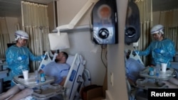 FILE - Dr. Manuel Gordillo speaks with Matthew Soriano, a coronavirus disease (COVID-19) positive patient, during medical rounds in the COVID unit at Sarasota Memorial Hospital in Sarasota, Florida, Feb. 11, 2021. 