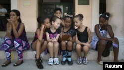 Children play with a tablet before performing at the first day of a contemporary urban dance festival in downtown Havana, April 15, 2015.