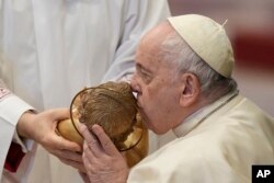 FILE - Pope Francis kisses a statue of Baby Jesus as he attends a Mass for the solemnity of St. Mary at the beginning of the new year, in St. Peter's Basilica at the Vatican, January 1, 2023.