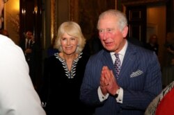 FILE - Britain's Prince Charles, with Camilla, Duchess of Cornwall, at his side, folds his hands in a "namaste" greeting, during a reception at Marlborough House, in London, Britain, March 9, 2020.