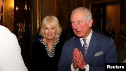FILE - Britain's Prince Charles, with Camilla, Duchess of Cornwall, at his side, folds his hands in a "namaste" greeting, during a reception at Marlborough House, in London, Britain, March 9, 2020. 