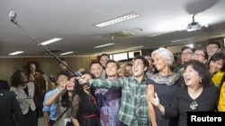 Mari Pangestu (kanan, baju hitam), mantan menteri perdagangan, berswafoto bersama Direktur Eksekutif Dana Moneter Internasional (IMF) Christine Lagarde dan para mahasiswa Universitas Indonesia usai acara diskusi di Depok, 1 September 2015. (Foto: Reuters)