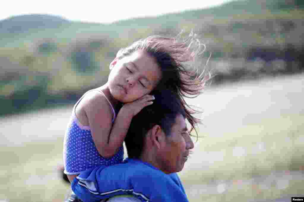 Rosendo Noviega, a 38-year-old migrant from Guatemala — part of a caravan of thousands from Central America en route to the United States — carries his daughter Belinda Izabel on his shoulders as he walks along the highway to Juchitan from Santiago Niltepec, Mexico, Oct. 30, 2018.