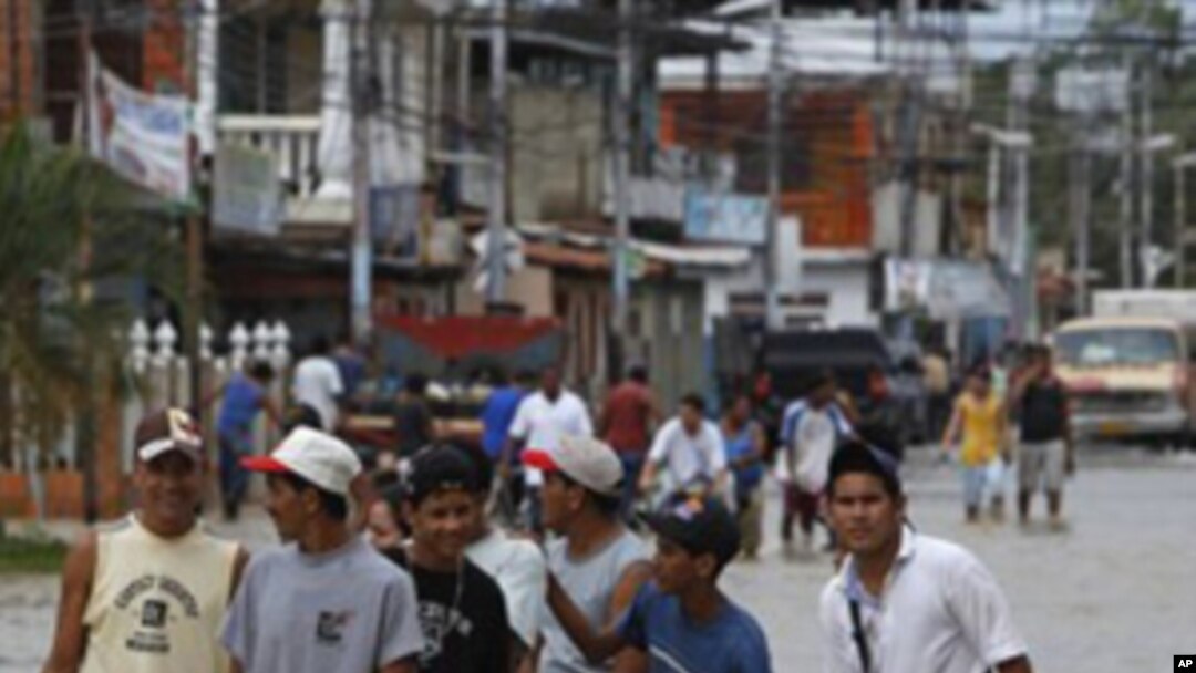 People walk on a street flooded in Rio Chico, central Venezuela, Saturday, Dec. 4, 2010.