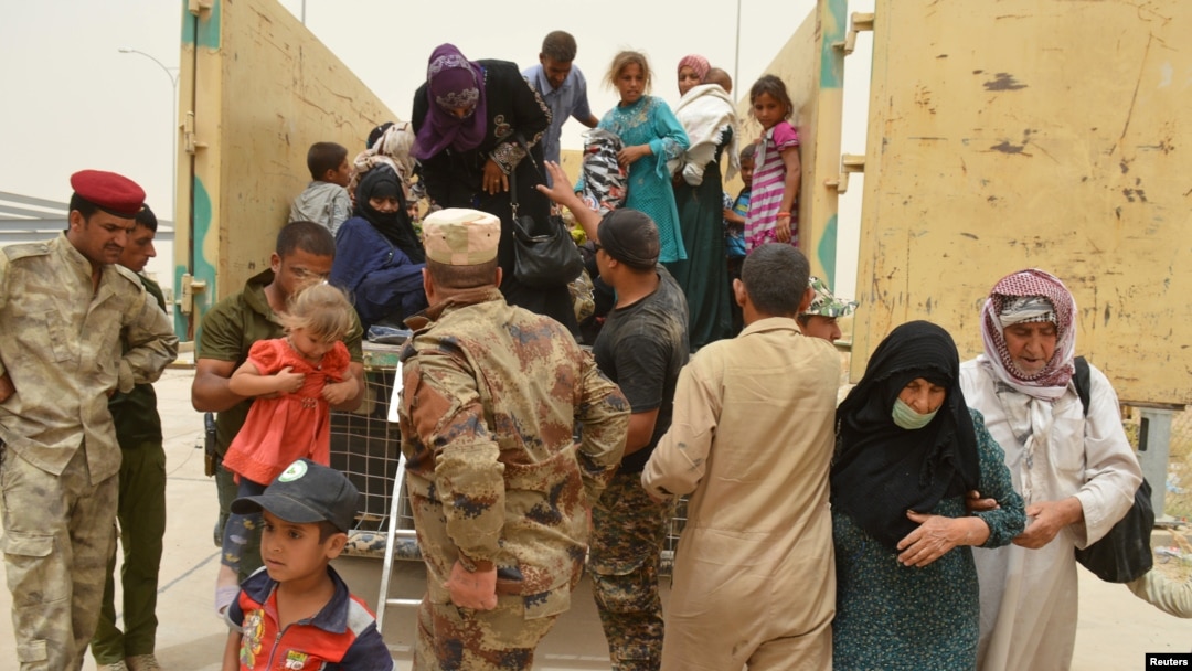 Iraqi soldiers help civilians, who fled from Falluja because of Islamic State violence, during a dust storm on the outskirts of Fallujah, Iraq, June 18, 2016