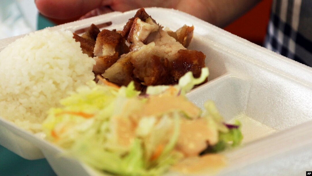 Belinda Lau, manager of the Wiki Wiki Drive Inn takeout restaurant in Honolulu, holds a polystyrene foam box containing an order of roast pork, rice and salad, March 14, 2019. 