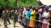 Kenyan police men walk past members of the public standing behind the cordoned off area outside the church where gunmen attacked worshippers attending a church service at the Coast coastal town of Mombasa, March 23, 2014. 