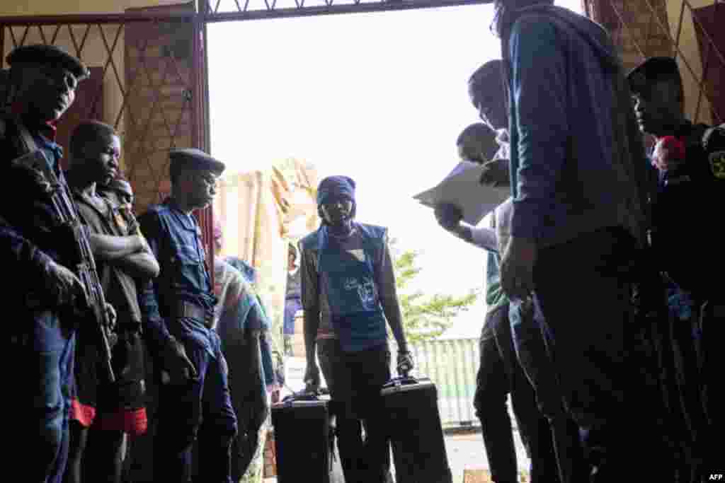 Des employés de la Commission électorale nationale indépendante (CENI) déchargent un camion de matériel de vote dans un bureau de vote alors qu'il était gardé par la police à Bukavu, le 28 décembre 2018.