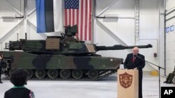 Duta Besar AS untuk Estonia James D. Melville Jr. berpidato di depan tank militer AS, dalam upacara serah terima pangkalan militer yang diperbaiki di Tapa, Estonia (15/12). (AP/Vitnija Saldava)