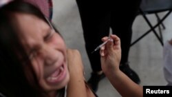 FILE PHOTO: A child receives a vaccination as part of the start of the seasonal flu vaccination campaign as a preventive measure due to the outbreak of coronavirus disease (COVID-19), in Santiago, Chile March 16, 2020. REUTERS/Ivan Alvarado/File Photo