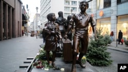 People pass a commemorative memorial statue to perpetuating the memory of the 'Kindertransport' (children transport) near Friedrichstrasse train station in central in Berlin, Germany, Dec. 17, 2018. 