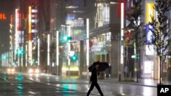 Un hombre cruza una calle en el distrito comercial Ginza bajo la lluvia provocada por el tifón Hagibis en Tokio, el sábado 12 de octubre de 2019. 