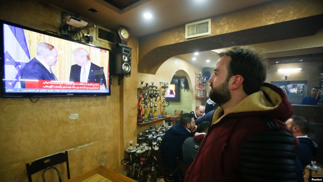 Seorang warga Palestina menonton konferensi pers gabungan Presiden AS Donald Trump dan Perdana Menteri Israel Benjamin Netanyahu, dari sebuah kafe di Hebron, Tepi Barat (15/2). (Reuters/Mussa Qawasma)
