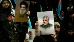 Warga mengangkat poster mendiang komandan Pasukan Garda Revolusi Iran, Jenderal Qassem Soleimani, kanan dan poster pemimpin Hizbullah yang terbunuh Hassan Nasrallah, selama upacara peringatan kematian Soleimani di Masjid Agung Imam Khomeini di Teheran, Kamis, 2 Januari 2025.