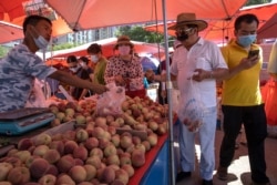 Residents wearing face masks to curb the spread of the coronavirus shop for fruit at an open air market in Beijing, China, June 15, 2020.