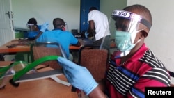 Des travailleurs préparent des écrans faciaux à partir de plastiques recyclés à l'atelier Zaidi Recyclers comme mesure pour arrêter la propagation de la maladie à coronavirus (COVID-19) à Dar es Salaam, en Tanzanie.