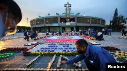 Un hombre enciende velas en nombre de los fieles en la Basílica de Guadalupe que está temporalmente cerrada para evitar multitudes en el tradicional día de celebración de la Virgen de Guadalupe, el 12 de diciembre, mientras sigue el brote de coronavirus.