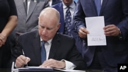 El gobernador Jerry Brown firma una copia de la medida ambiental SB100, que establece un ajuste gradual de todos los combustibles fósiles del sector eléctrico del estado, para el año 2045. 