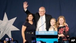 El primer ministro australiano Scott Morrison, segundo a la izquierda, llega al escenario para hablar con sus partidarios acompañado por su esposa, Jenny, a la izquierda, y sus hijas Lily y Abbey, a la derecha, después de que su oponente accediera a las elecciones.