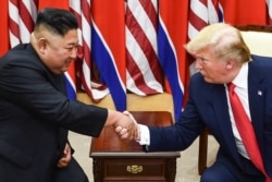 FILE - In this file photo taken on June 30, 2019, North Korea's leader Kim Jong Un (L) and US President Donald Trump shake hands during a meeting on the south side of the Military Demarcation Line that divides North and South Korea.