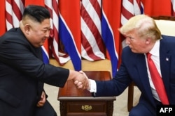 FILE - In this file photo taken on June 30, 2019, North Korea's leader Kim Jong Un and US President Donald Trump shake hands during a meeting on the south side of the Military Demarcation Line that divides North and South Korea.