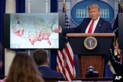 FILE - President Donald Trump gestures towards a screen displaying a graphic on the coronavirus outbreak as he speaks during a news conference at the White House, Thursday, July 23, 2020, in Washington. (AP Photo/Evan Vucci)