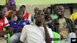 A group of youths monitor a horse race after placing a bet in Harare, Zimbabwe, Jan. 18, 2014. 