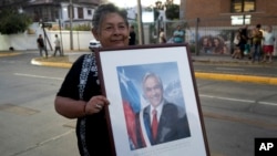 A supporter of the late Chilean President Sebastian Pinera holds a framed photo of him, in Santiago, Chile, Feb. 6, 2024. The two-time former president died Tuesday in a helicopter crash. He was 74.