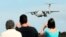 Spectators take photos of a Chinese Ilyushin IL-76 aircraft as it comes in for a landing at Perth International Airport after returning from the ongoing search operations for missing Malaysia Airlines Flight 370 in Perth, Australia, Thursday, April 10, 
