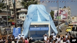 Palestinians applaud unveiling of a symbolic chair supporting the Palestinian statehood bid, in the West Bank city of Ramallah, September 20, 2011.