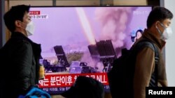 Men walk past a TV broadcasting a news report on North Korea firing a ballistic missile off its east coast, in Seoul, South Korea, Nov. 3, 2022. 