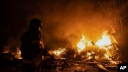 En esta imagen suministrada por el Ministerio ucraniano de Situaciones de Emergencia, los bomberos apagan un incendio provocado por restos de un cohete ruso derribado por defensas antiaéreas durante un ataque a Kiev, Ucrania, la madrugada del martes 16 de mayo de 2023.