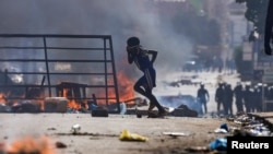 A boy runs past barricades as Senegalese demonstrators clash with riot police during a protest against the postponement of the February 25 presidential election, in Dakar, Senegal, February 4, 2024. 