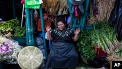 FILE - A vegetable vendor prays as medical workers from the Ministry of Health seek volunteers for new coronavirus tests at La Terminal market in Guatemala City, May 21, 2020. 