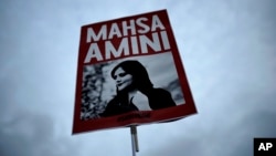 FILE - A woman holds a placard with a picture of Iranian woman Mahsa Amini during a protest against her death, in Berlin, Germany, on Sept. 28, 2022. Iran is responsible for the "physical violence" that led to Amini's death, a U.N. fact-finding mission said on March 8, 2024.