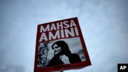 A woman holds a placard with a picture of Iranian woman Mahsa Amini during a protest against her death, in Berlin, Germany, on Sept. 28, 2022. (AP Photo/Markus Schreiber)