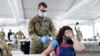 FILE - A woman receives the Pfizer COVID-19 vaccine at a FEMA vaccination center at Miami Dade College, April 5, 2021.