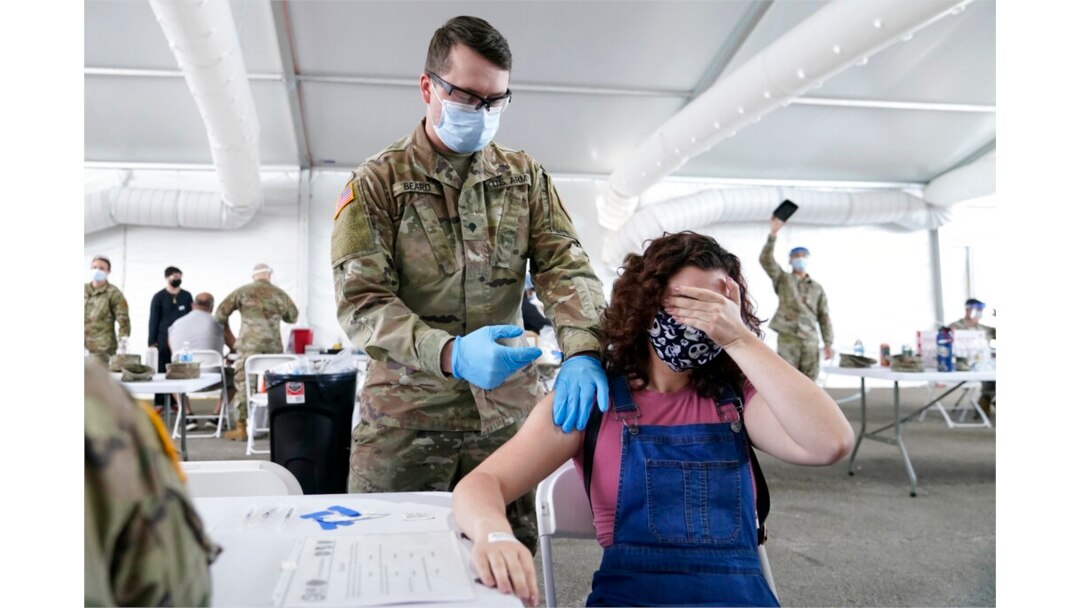 Seorang wanita menutupi matanya untuk menghindari melihat jarum saat disuntik vaksin COVID-19 Pfizer di pusat vaksinasi FEMA di Miami Dade College, Miami, 5 April 2021.