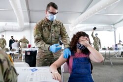 Seorang wanita menutupi matanya untuk menghindari melihat jarum saat disuntik vaksin COVID-19 Pfizer di pusat vaksinasi FEMA di Miami Dade College, Miami, 5 April 2021.